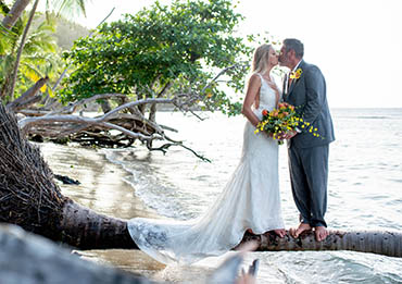 Loving couple kissing on a palm tree overhanging the water in St. Thomas USVI.