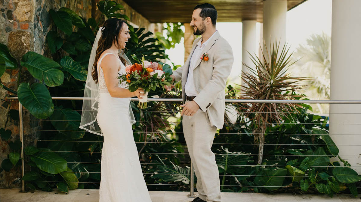 Married couple kissing barefoot on a palm tree overhanging the beautiful waters of St. Thomas.