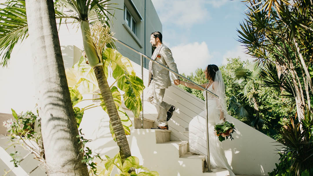 Husband holding wife's hand in front of Greetings from St Thomas mural in the USVI.