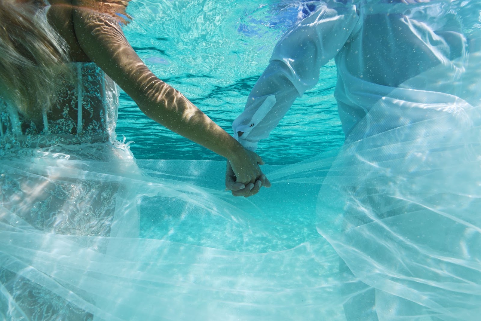 Married couple kissing barefoot on a palm tree overhanging the beautiful waters of St. Thomas.