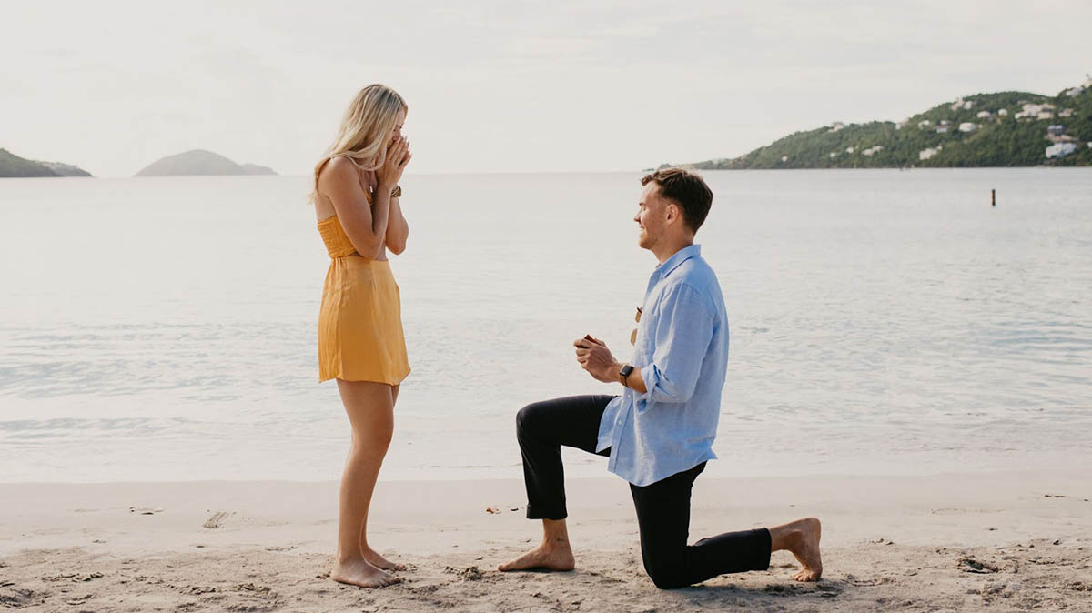 Married couple kissing barefoot on a palm tree overhanging the beautiful waters of St. Thomas.