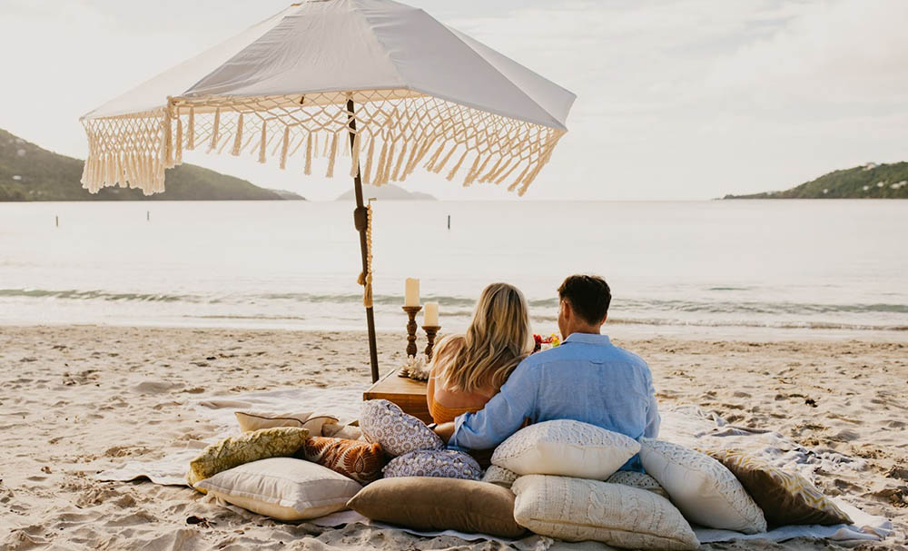 Married couple walking happily barefoot in the sand in St. Thomas.