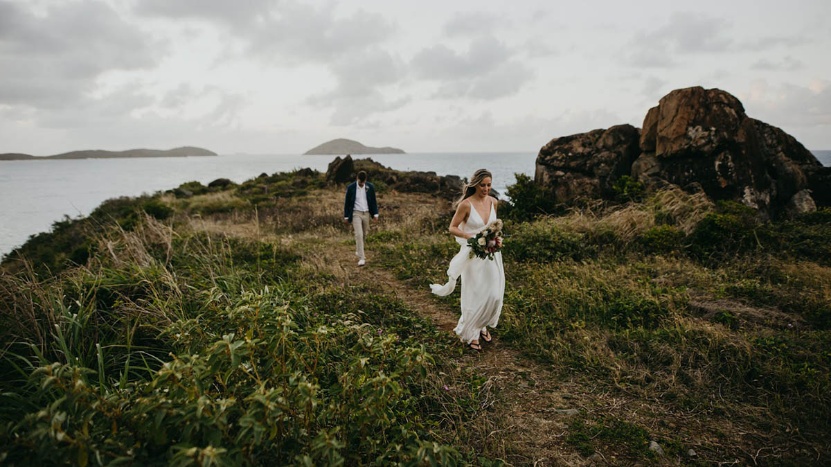 Married couple walking happily barefoot in the sand in St. Thomas.