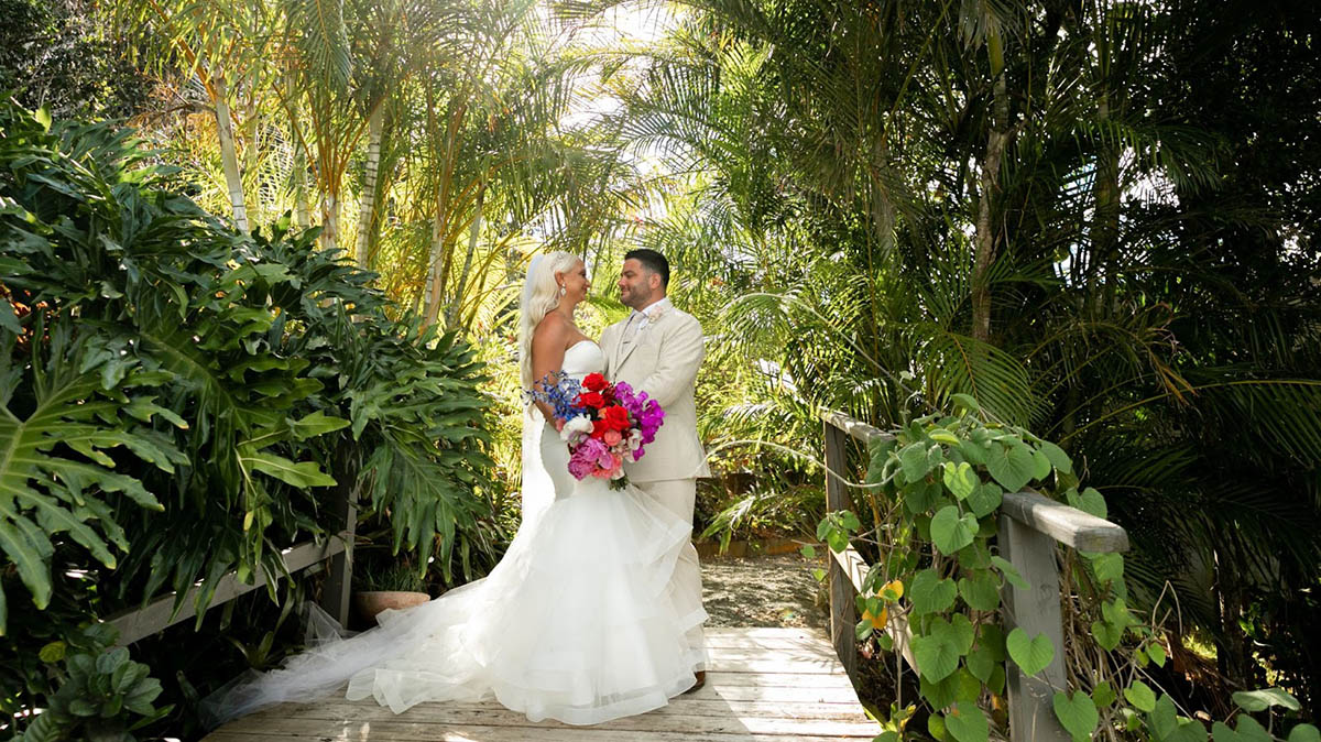 Married couple kissing barefoot on a palm tree overhanging the beautiful waters of St. Thomas.