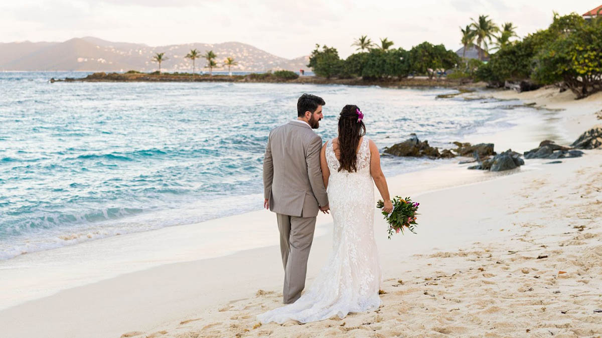 Married couple kissing barefoot on a palm tree overhanging the beautiful waters of St. Thomas.